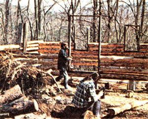 Shown is a photo of Jim Hilberer and Terry Atwater working on Hilberer's log cabin.